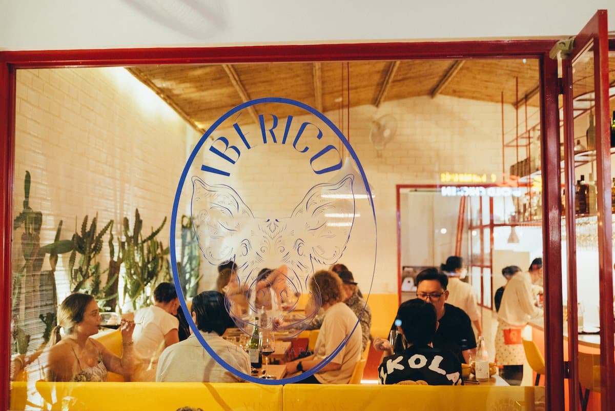 Guests celebrating at IBÉRICO, seen through the etched glass door